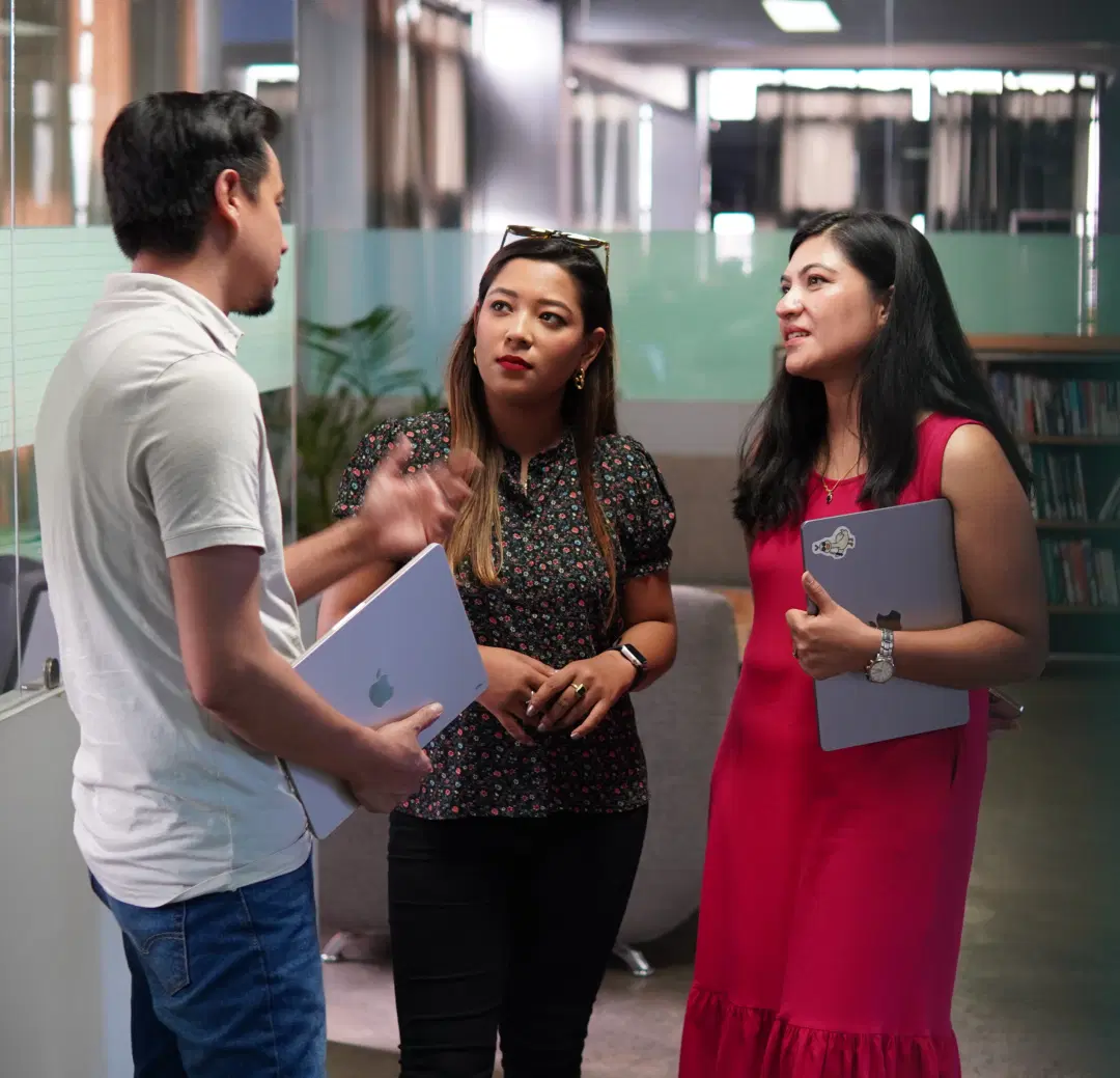 Three Leapfroggers (employees) discussing in open space, nurturing their curiosity.